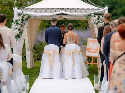 Para młoda podczas ceremonii ślubnej. Wesele w plenerze, pod namiotem ozdobionym kwiatami.