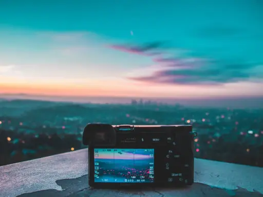 Aparat fotograficzny na tle miejskiego krajobrazu o zachodzie słońca. Różnorodne rodzaje światła tworzą magiczną atmosferę.