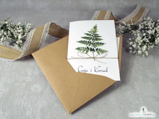 Eleganckie zaproszenie ślubne z paprocią i imionami pary. W zestawie koperta i ozdobna wstążka. To, co musi zawierać zaproszenie, to jego piękny design.