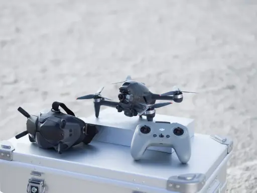 Szybkie drony, gogle FPV i kontroler gotowe do akcji na plaży.