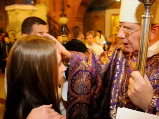 Biskup namaszcza młodą dziewczynę podczas bierzmowania. Czy bierzmowanie jest obowiązkowe? To ważny sakrament.