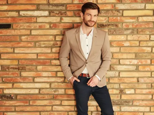 Mężczyzna w beżowej marynarce i granatowych spodniach, idealny na wesele w stylu casual.