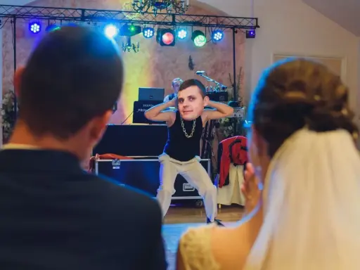 Zabawny pan z twarzą na głowie tańczy na weselu, tworząc nowoczesne zabawy na oczepiny.