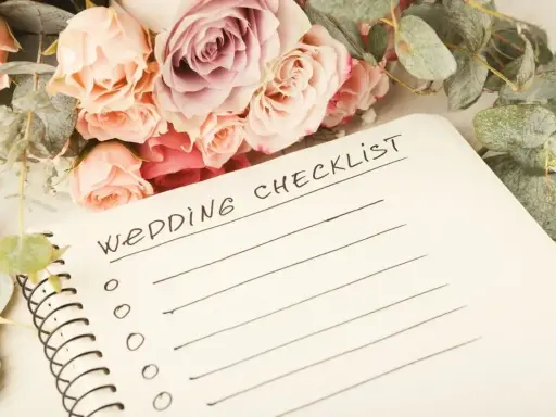 Bukiet róż i eukaliptusa obok notatnika z napisem "Wedding Checklist". Idealna inspiracja, co zabrać na wesele.