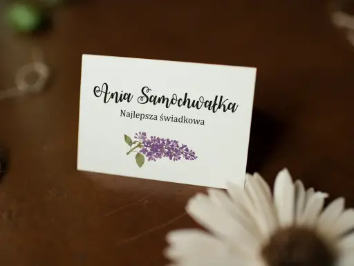 Winietka z napisem "Ania Samochwałka Najlepsza świadkowa" i gałązką bzu. Idealna inspiracja, jak wypisać winietki dla rodziców.