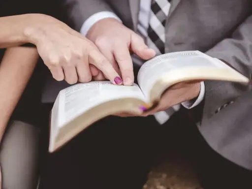 Dłonie pary wskazują na tekst w Biblii, przygotowując się do wspólnych czytań na ślubie.