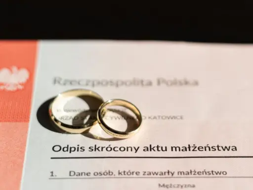 Złote obrączki na odpisie skróconym aktu małżeństwa po ślubie cywilnym.
