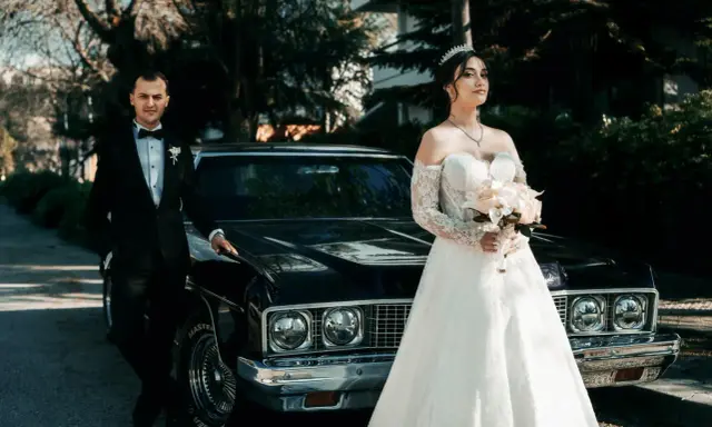 Para, w eleganckim czarnym garniturze, i panna młoda w sukni z koronki, z bukietem w dłoni, stoją obok zabytkowego samochodu. Nawet jeśli nie mam świadków na ślub, ten dzień jest nasz.