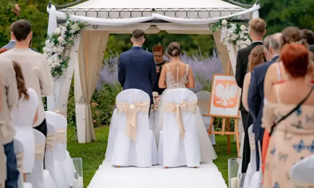Para młoda podczas ceremonii ślubnej. Wesele w plenerze, pod namiotem ozdobionym kwiatami.