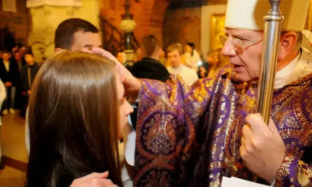 Biskup namaszcza młodą dziewczynę podczas bierzmowania. Czy bierzmowanie jest obowiązkowe? To ważny sakrament.