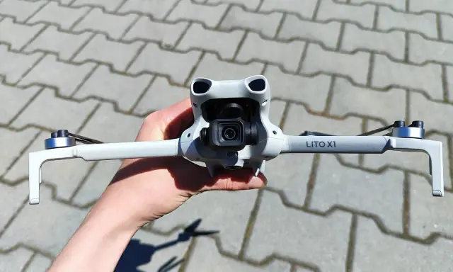 Ręka trzyma najnowszy dron DJI, gotowy do lotu. Jego kompaktowa konstrukcja i zaawansowana kamera zapowiadają niesamowite ujęcia.