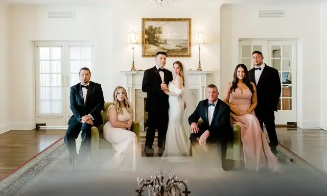 Para młoda z rodziną pozuje do zdjęcia przed ślubem. Eleganckie stroje i uroczysta atmosfera.