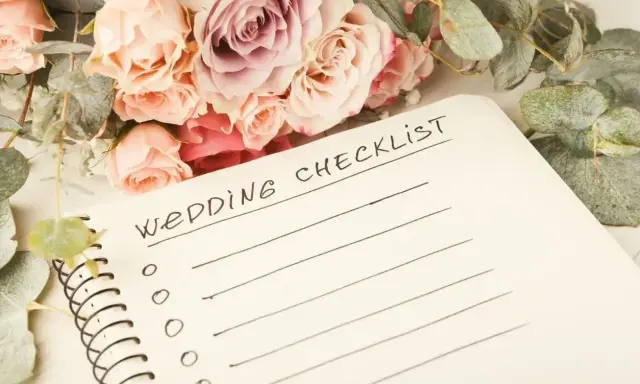 Bukiet róż i eukaliptusa obok notatnika z napisem "Wedding Checklist". Idealna inspiracja, co zabrać na wesele.