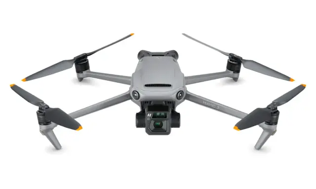 Szary dron DJI Mavic 3 z kamerą i czterema śmigłami. Jego niewielka waga pozwala na długie loty.