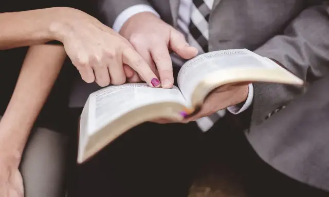 Dłonie pary wskazują na tekst w Biblii, przygotowując się do wspólnych czytań na ślubie.