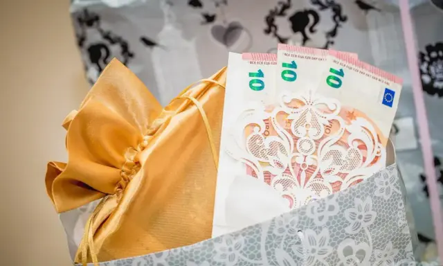 Elegancki sposób na to, jak zapakować pieniądze na ślub: banknoty 10 euro w ozdobnej kopercie, w złotej sakiewce, w ozdobnej torbie.