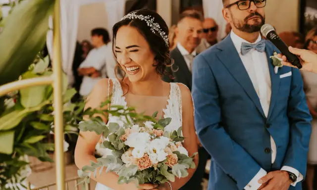 Szczęśliwa panna młoda z bukietem, obok pana młodego w garniturze. Ceremonia ślubu cywilnego, konsekwencje tej decyzji są radosne.