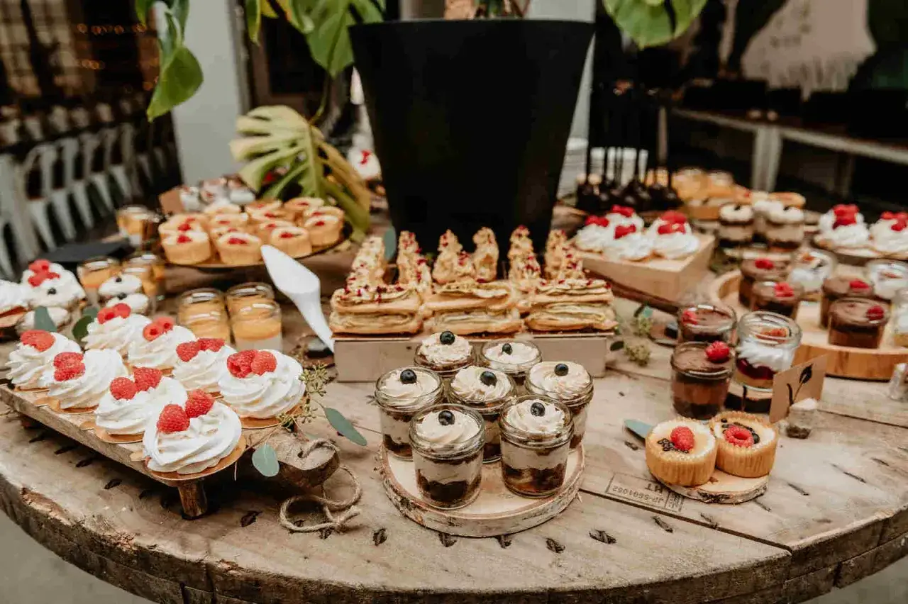 Eleganckie ciasta na wesele bez kremu: bezy z malinami, mini serniczki, deserki w słoiczkach i kruche ciasteczka.