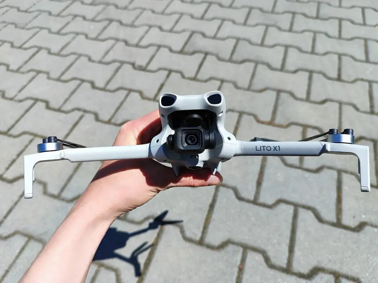 Ręka trzyma najnowszy dron DJI, gotowy do lotu. Jego kompaktowa konstrukcja i nowoczesny design zachwycają.