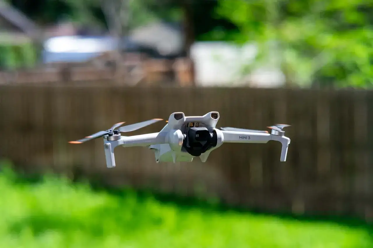 Biały dron Mini 3 z kamerą w locie, gotowy do eksploracji z zasięgiem 10km.