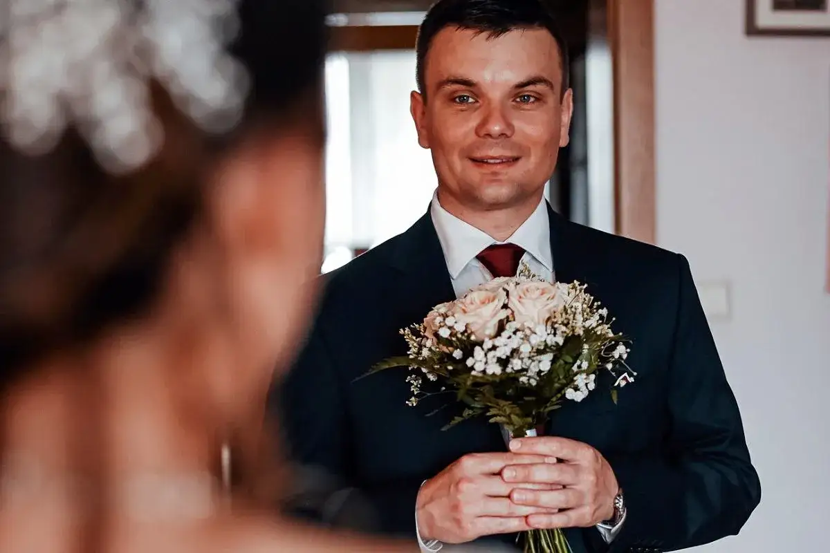Pan młody z bukietem róż w dłoniach, uśmiecha się do swojej wybranki. Czy były ksiądz może wziąć ślub kościelny? To pytanie, które nurtuje wiele par.