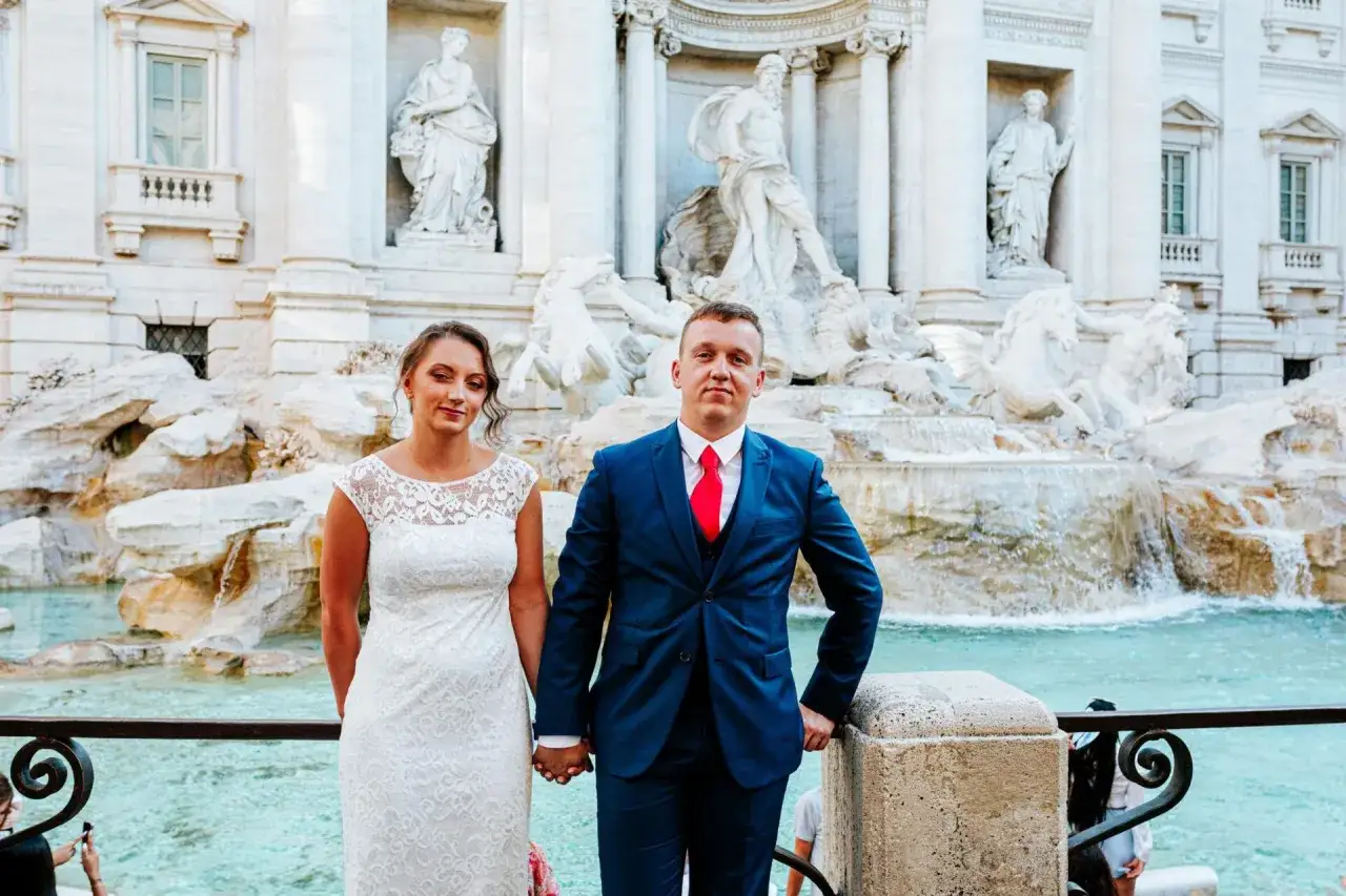 Para młoda pozuje przy Fontannie di Trevi, celebrując swój ślub w Rzymie.